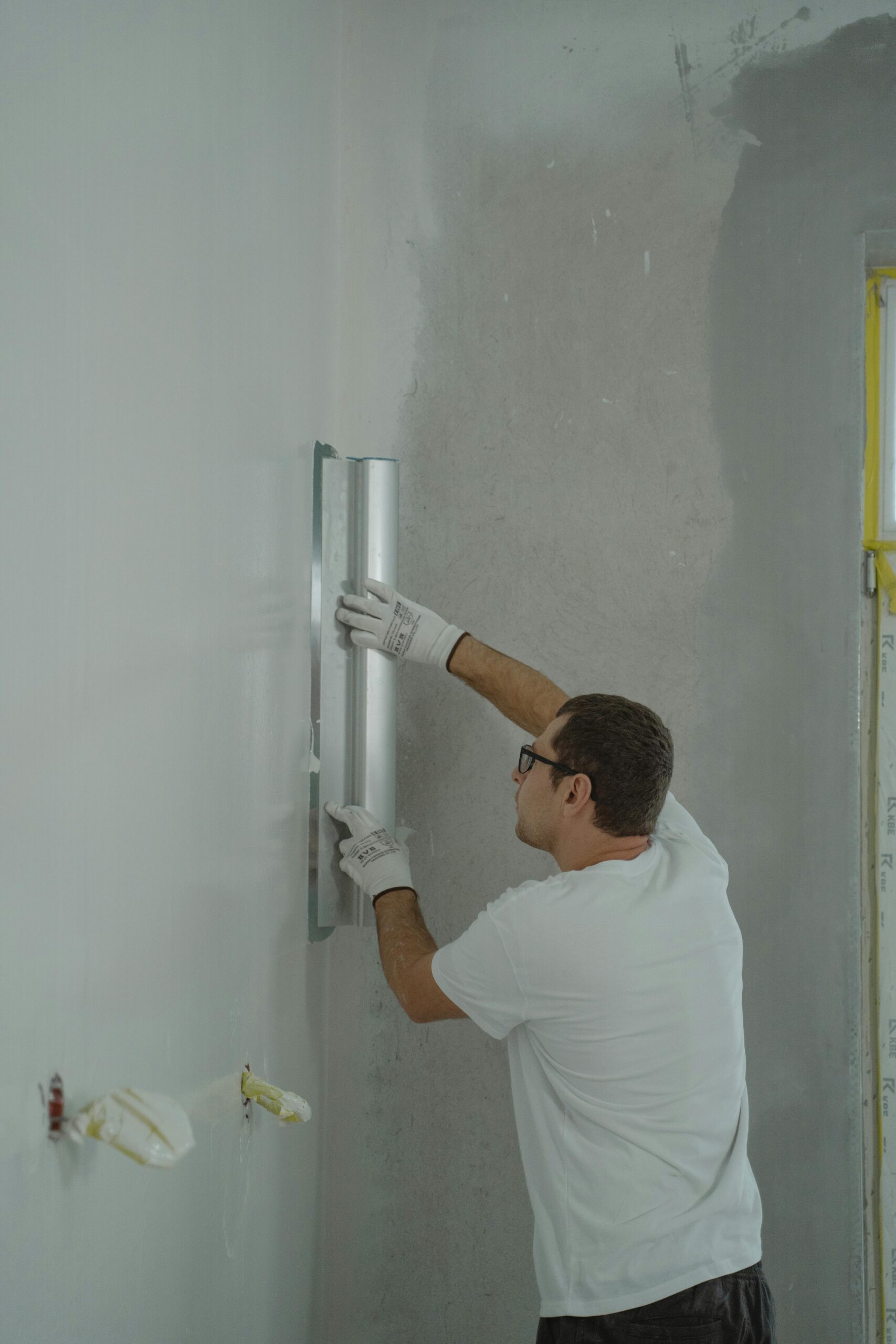 A man skillfully renovates a wall using tools in a modern interior setting.